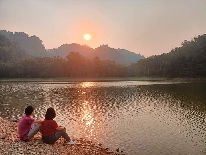 Pha Day Lake in the sunset, with mist over the water and forested hills around it