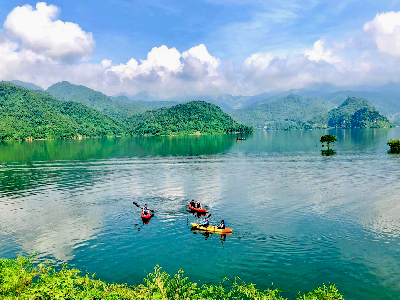 A team paddling two kayaks side by side on still morning water, soft golden-hour light, limestone hills in the background (Source: Collected)
